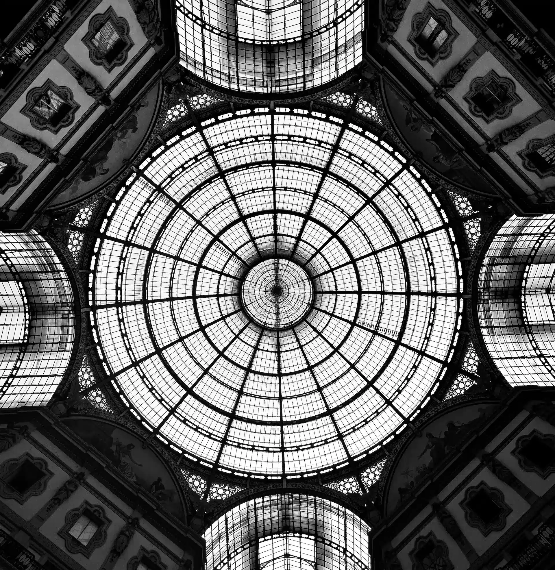 Vue en contre-plongée d'une coupole vitrée monumentale en noir et blanc au style art nouveau.